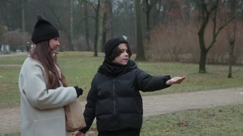 A trusting wild bird hand-feeds from a patient child's palm in a park Stock Footage 312335197