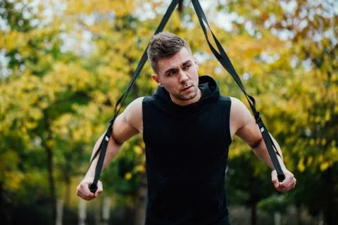 TRX training. Man Instructor at the park doing Excersise. Fitness workout Stock Photos
