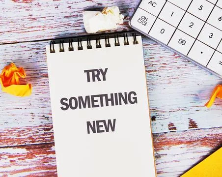TRY SOMETHING NEW words on a blank sheet of notepad located on old boards Stock Photos