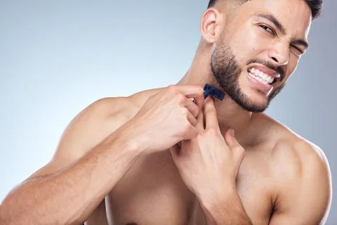Trying to avoid nicks and cuts. a young man shaving against a studio background. Stock Photos
