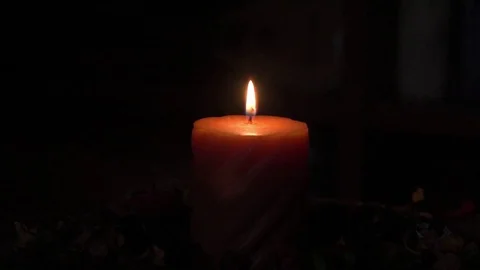 Trying to blow out the flame of an orange candle. Stock Footage 101876260