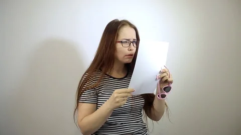 Trying on different glasses to read the text Caucasian middle-aged woman with Stock Footage 98809100