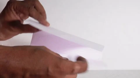 Trying to fold thin white paper 7 times, fold paper only 6 time Stock Footage 246542321