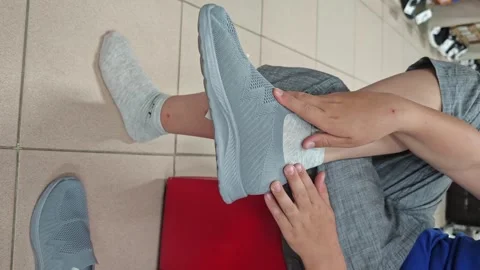 Trying on gray shoes with gray socks during a shopping trip at a store Stock Footage 338128002