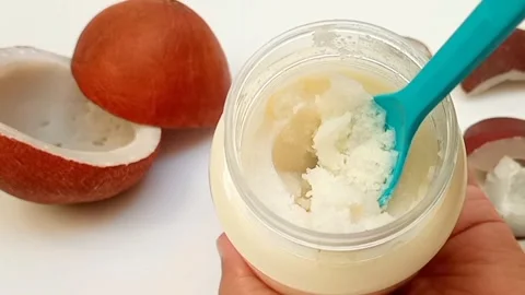 Trying to spoon out of hard coconut oil from a jar with a plastic spoon Stock Footage 275670717