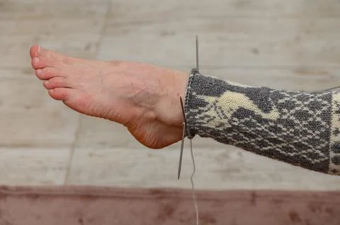 Trying on an unfinished patterned wool sock with knitting needles Stock-Fotos
