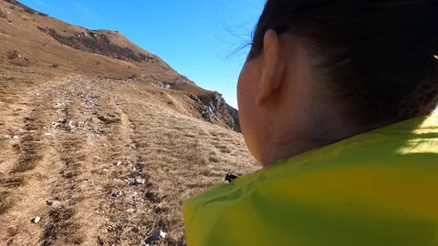 TS Female hiker walking up a mountain on a narrow grassy path in sunshine Stock Footage 126163853