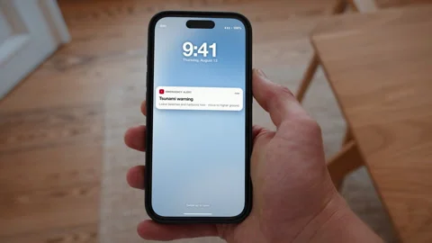 Tsunami warning alert on a smartphone lock screen, coastal emergency management Stock Footage 346142383