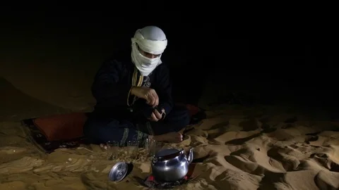 Tuareg man making tea in a desert at night Stock Footage 84137082
