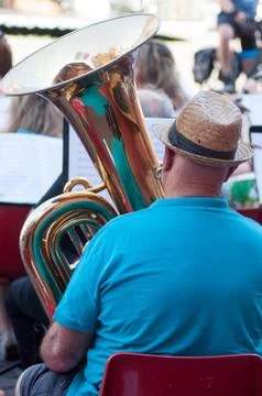 Tuba player with hat on back view playing in band  in tne street Foto stock