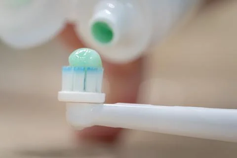 Tube of toothpaste pouring paste on an electric toothbrush, macro photography. Foto stock