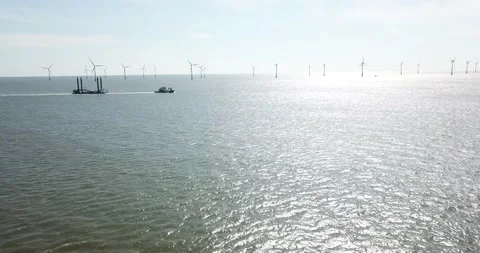 Tug boat towing large load infront of the Scroby Sands Wind Farm Stock Footage 148296229