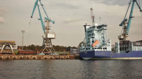 Tug passing by with a container ship and train loading cargo by cranes Stock Footage 41851972