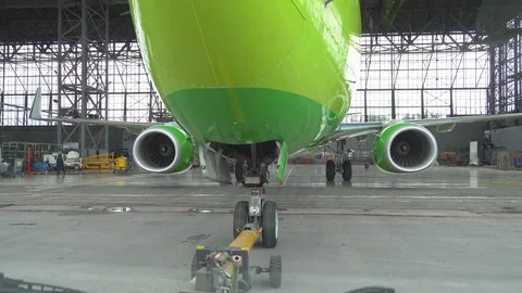 Tug pulls the plane out of the hangar. After repair, the aircraft is pulled out  Stock Footage 84389368
