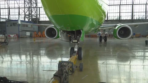 Tug pulls the plane out of the hangar. After repair, the aircraft is pulled out  Vídeo Stock 84581540