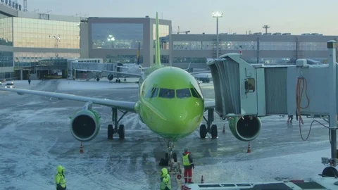 Tug pushing back the green plane. Winter Stock Footage 78729498