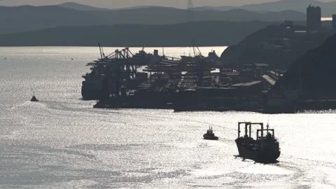 Tug takes a large cargo ship out of the port into the open sea along the Strait Stock Footage 134861052