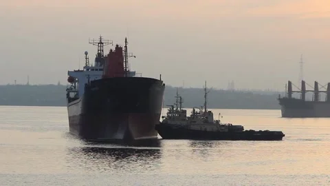A tugboat is heading towards a large cargo ship for transport to the dock. A car Stock Footage 137255885