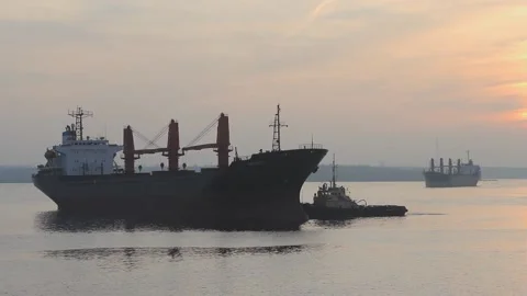 A tugboat is heading towards a large cargo ship for transport to the dock. A car Stock Footage 137255908