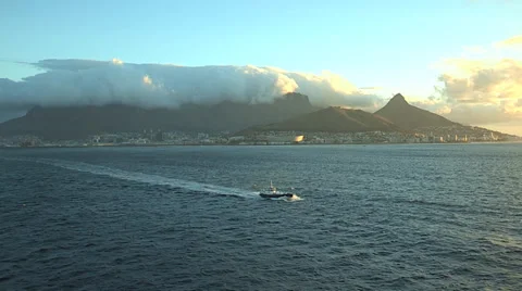 Tugboat moving in the Atlantic Ocean with Cape Town behind at sunset. Stock Footage 34103992