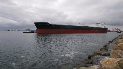 Tugboat pulling cargo ship away in the harbor Stock Footage 116909251