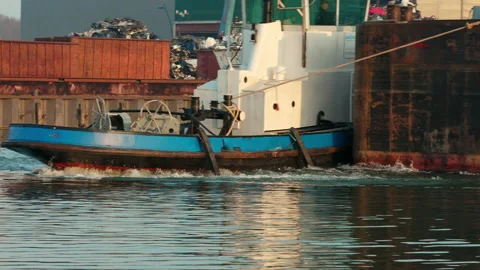 A tugboat pulls a barge through a narrow basin in the industrial port of 스톡 동영상 163038579
