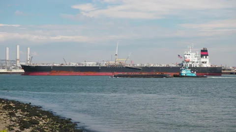 Tugboat pushes small barge in front of Giant Tanker  4K Stock Footage 141960262