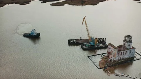 The tugboat sails to the barge, from which the crane unloads the sand. Aerial Stock Footage 220632622