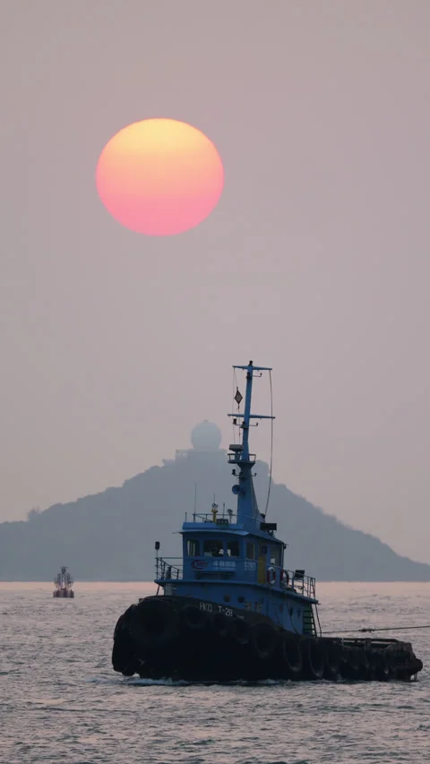 Tugboat sails at sunset dragging some vessel behind it by wire rope Stock Footage 304652860