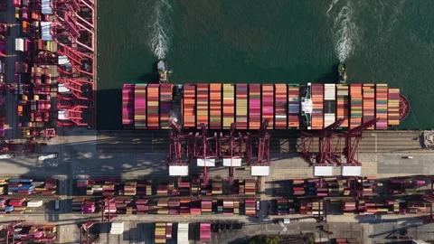 Tugboats moving large container ship from a busy commercial port terminal Stock Footage 329261663