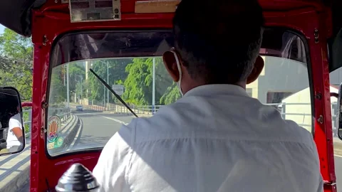 Tuk-tuk driver navigating through a busy urban street. Video stock 302691634