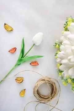 A tulip flower next to decorative threads, dried roses on a white cloth Stock Photos