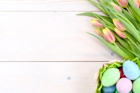 Tulips  and easter eggs in basket on wooden background. Backdrop with empty s Stock Photos