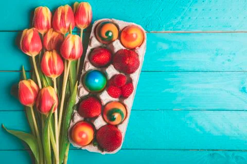 Tulips bouquet and easter eggs on blue table Stock Photos