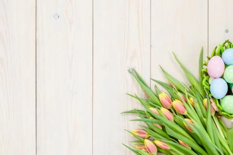Tulips  with easter eggs in basket over wooden background.  Backdrop with emp Stock Photos