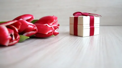 Tulips lay down next to the gift box with a red bow Stock Footage 60065953