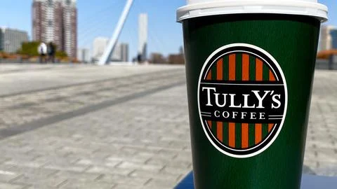 Tully's Coffee paper cup featuring the brand logo with a scenic blurred bac.. Stock Photos