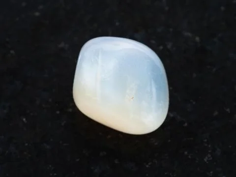 Tumbled translucent moonstone gemstone on dark Stock Photos