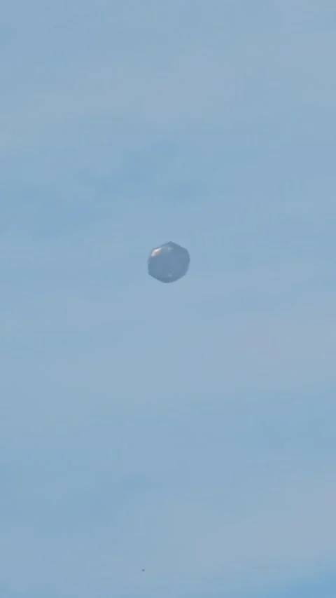 Tumbling Silver Balloon Floating High in a Clear Blue Sky Stock Footage 332027324