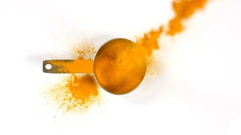 Tumeric powder poured in slow motion into a stainless steel measuring utensil Vidéo 88517872