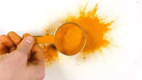 Tumeric powder in slow motion with a stainless steel measuring utensil taken  Stock Footage 88517833