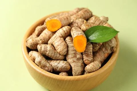 Tumeric rhizomes with leaf in bowl on light green background, closeup Stock Photos
