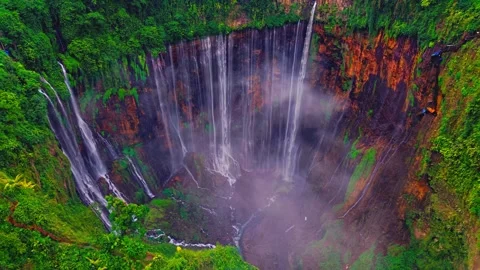 Tumpak sewu waterfall flowing down into misty tropical canyon captured Stock Footage 343696538