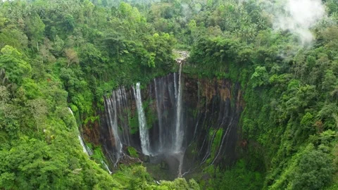 Tumpak Sewu Waterfall Java Indonesia Drone Through Clouds Wide Pan Down Video stock 305117111