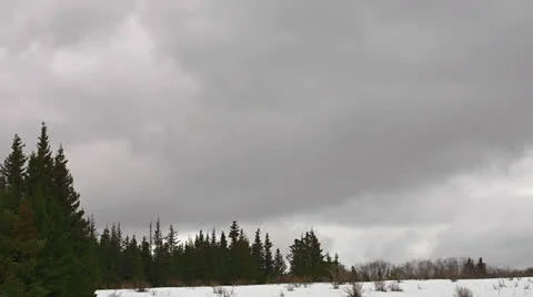 Tumultuous Storm Clouds over Forest and Snow fast Stock Footage 23357524