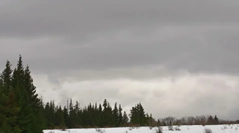Tumultuous Storm Clouds over Forest and Snow slow Stock Footage 23357589