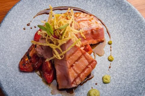 Tuna fillet on a parrilla with rostized jitomate in marmol plate. Stock Photos