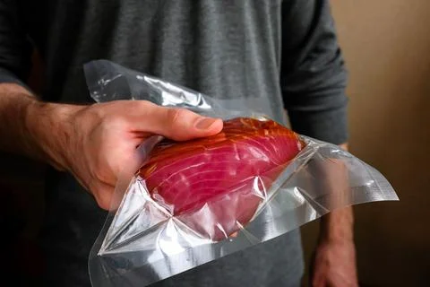 Tuna in the package. A man holding a packed red fish in his hand Stock Photos