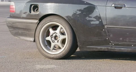 Tuned black drift car with worn out wheel drives away Stock Footage 166978744