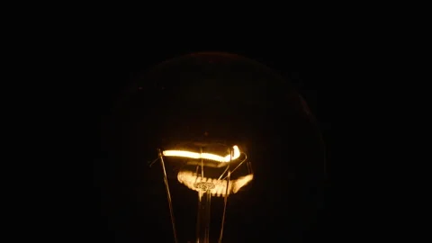 Tungsten light bulb light turns on and off cozy on black background Stock Footage 236822431